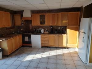 a kitchen with wooden cabinets and a white refrigerator at Grand Appartement avec cheminée dans maison, parking gratuit in Mionnay
