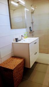 een badkamer met een wastafel, een spiegel en een rieten kruk bij Gîte Le bel Epi in Vany