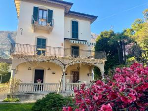 a large white house with a balcony and pink flowers at magnolia in Lenno