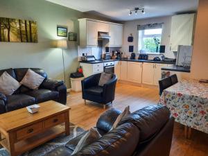 a living room with a couch and a kitchen at Snowdrop Cottage - W43121 in Goxhill