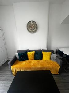 a living room with a couch with a clock on the wall at Wellington Apartment in Glasgow