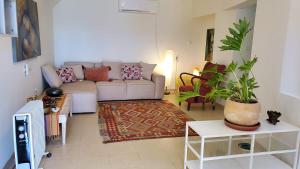 ein Wohnzimmer mit einem Sofa und einer Topfpflanze in der Unterkunft פינה ללב in Rosch Pina