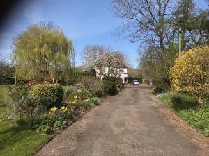 uma estrada de terra com flores ao lado de uma casa em Spacious eco-energy timber barn in Chadbury em Offenham