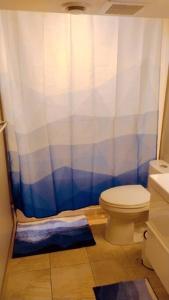 a bathroom with a toilet and a blue and white shower curtain at *Luxury 1 BR Suite - Own Access* in Sherwood Park