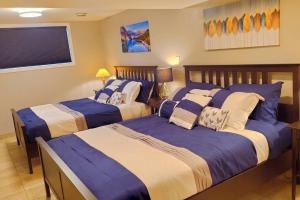 two beds in a bedroom with blue and white at *Luxury 1 BR Suite - Own Access* in Sherwood Park