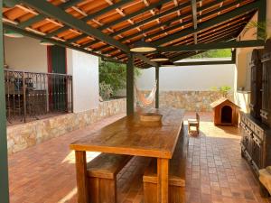 una mesa de madera en un patio bajo una pérgola en Casa no Centro Histórico de Catas Altas, en Catas Altas