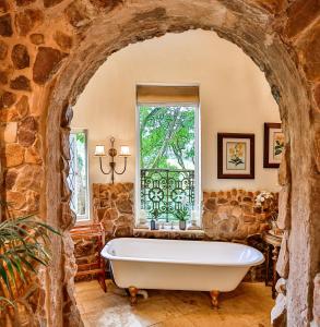 a bath tub in a stone bathroom with a window at MacLeod House Guest Cottage in Kloof