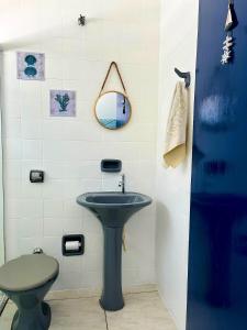 a bathroom with a sink and a mirror and a toilet at Pousada Ilha de Santorini in Bertioga
