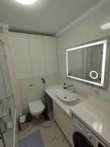 y baño con lavabo, aseo y espejo. en 1 комнатная квартира в ЖК Алмалы,район Алматы Арена, en Almaty