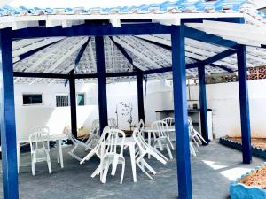 a group of white chairs and tables on a patio at Pousada Ilha de Santorini in Bertioga