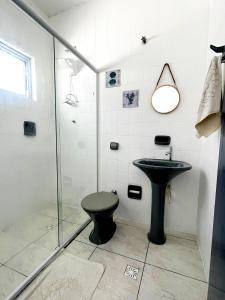 a bathroom with a shower and a toilet and a sink at Pousada Ilha de Santorini in Bertioga