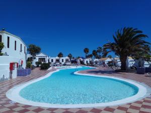 a swimming pool at a resort with palm trees and houses at Casita Montecastillo K4 - 2 bedrooms in Caleta De Fuste