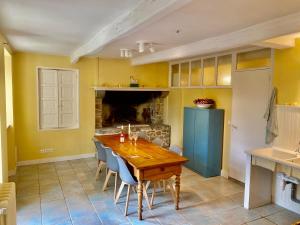 uma sala de jantar com uma mesa de madeira e uma lareira em Hübsches Landhaus der Familie mit eigenem Garten em Heugueville-sur-Sienne