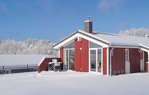 eine rote Scheune mit Schnee auf dem Boden in der Unterkunft Ferienhaus Venus B in Sankt Andreasberg