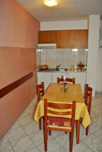 a kitchen with a wooden table with chairs and a counter at Apartments Buljevic in Vrboska +23 photos