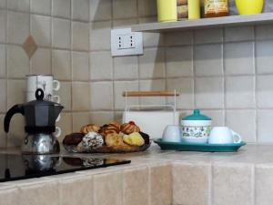 - un comptoir avec un plateau de pâtisseries et une cafetière dans l'établissement Casa Bianca, à Gagliano del Capo