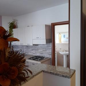 Una cocina con gabinetes blancos y un horno de estufa. en La Fortezza casa vacanze & appartament, en Castelsardo
