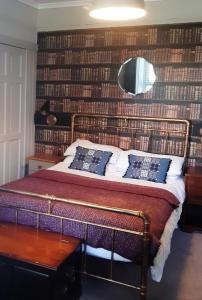 a bedroom with a bed with a wall of books at Pondside Cottage in Carmarthen