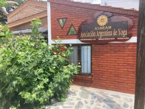 un edificio de ladrillo rojo con un cartel. en Asharam Asociación Argentina de Yoga en Mina Clavero