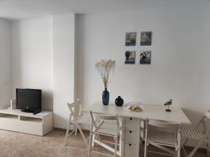 jadalnia ze stołem i krzesłami oraz telewizorem w obiekcie Rocachica Edén Beach 41 w mieście Torremolinos