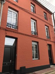 - un bâtiment en briques rouges avec des portes et des fenêtres noires dans l'établissement Maison Gabriel Appartement PLUME, à Abbeville