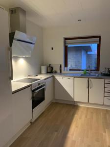 a kitchen with white appliances and a wooden floor at SleepOver in Rødby! Few minutes from Femern Tunnel and Ferry to Puttgarden in Rødby
