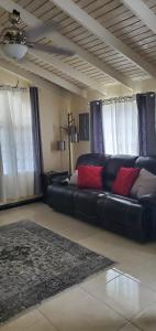 a living room with a black leather couch with red pillows at Hillside Retreat in Gated Community Close to Beach in Montego Bay