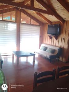 sala de estar con sofá, TV y mesa en Casa Alfalfal en San José de Maipo