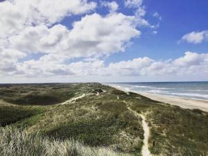 a view of a beach and the ocean on a cloudy day at Fjand Badeby - Guesthouse, Cottages and Colony in Ulfborg