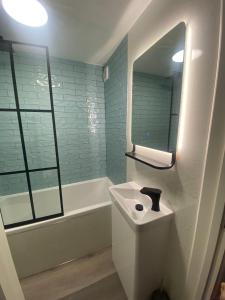 uma casa de banho com um lavatório, uma banheira e um espelho. em Lovely 3 bed ground floor flat with free parking em Swanage