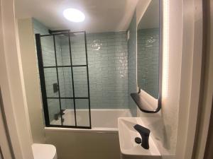 a bathroom with a tub and a sink and a mirror at Lovely 3 bed ground floor flat with free parking in Swanage