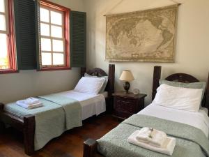 a room with two beds and a map on the wall at Casa no Centro Histórico de Catas Altas in Catas Altas +99 photos