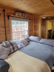 Cama grande en habitación con ventana en The Cabin at Forestview Farm en Greenisland