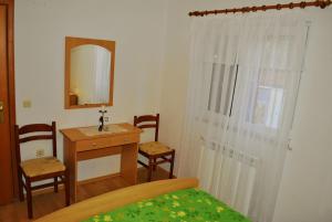 a bedroom with a bed and a desk and a mirror at Apartments Buljevic in Vrboska