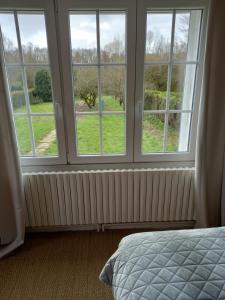 a bedroom with three large windows and a bed at Au bord du Vilpion in Marle-et-Behaine