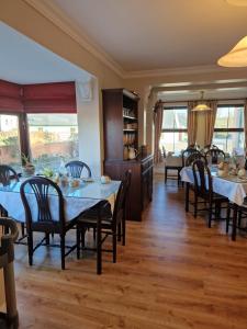 a dining room with tables and chairs and windows at Churchfield B&B in Doolin