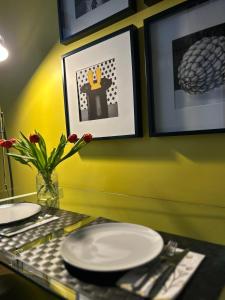 einen Tisch mit Tellern und Küchenutensilien an einer gelben Wand in der Unterkunft Castle Apartaments host Kaunas with free parking in Kaunas