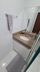 a bathroom with a sink and a mirror at Apartamento Confortável e Espaçoso in Sinop