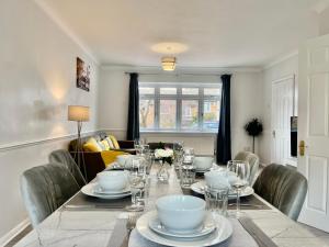 a dining room with a table with plates and glasses at Stylish 3 Bed Chigwell Home with Free Parking in Chigwell +21 photos