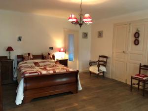 a bedroom with a bed and two chairs and a chandelier at La Glycine in La Canourgue