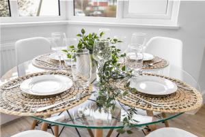a glass table with plates and glasses on it at Star London Vivian Avenue 2- Bed Abode in The Hyde