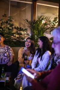 un groupe de personnes assises sur un canapé avec un microphone dans l'établissement Black Llama Hostel Miraflores, à Lima