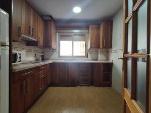 a kitchen with wooden cabinets and a window at LOW COST-PERGAR TORRENUEVA COSTA-wifi in Torrenueva