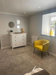 um quarto com uma cadeira amarela e uma cómoda em Sunny Corner - lovely 2 bedroom appt em Redruth