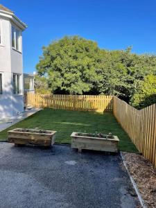 a yard with a wooden fence and two benches at Sunny Corner - lovely 2 bedroom appt in Redruth