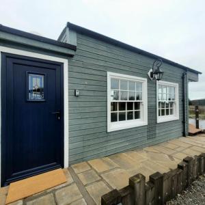 una casa azul con una puerta y ventanas azules en The Cabin at Forestview Farm en Greenisland