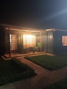 a house at night with a green chair in the yard at Wooden Knee Cottages Nanyuki in Nanyuki