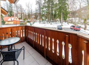 een balkon met een tafel en stoelen aan een houten hek bij Apartamenty Sun & Ski Willa Nad Strumieniem Nadrzeczna 3D i 3E - centrum 300m in Karpacz
