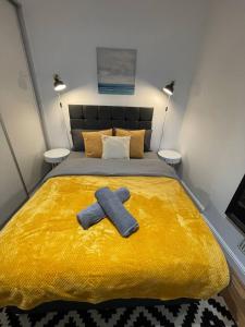 a yellow bed with a pair of towels on it at Cosmopolitan Stays in London