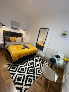 a bedroom with a bed with a yellow blanket and a table at Cosmopolitan Stays in London +24 photos